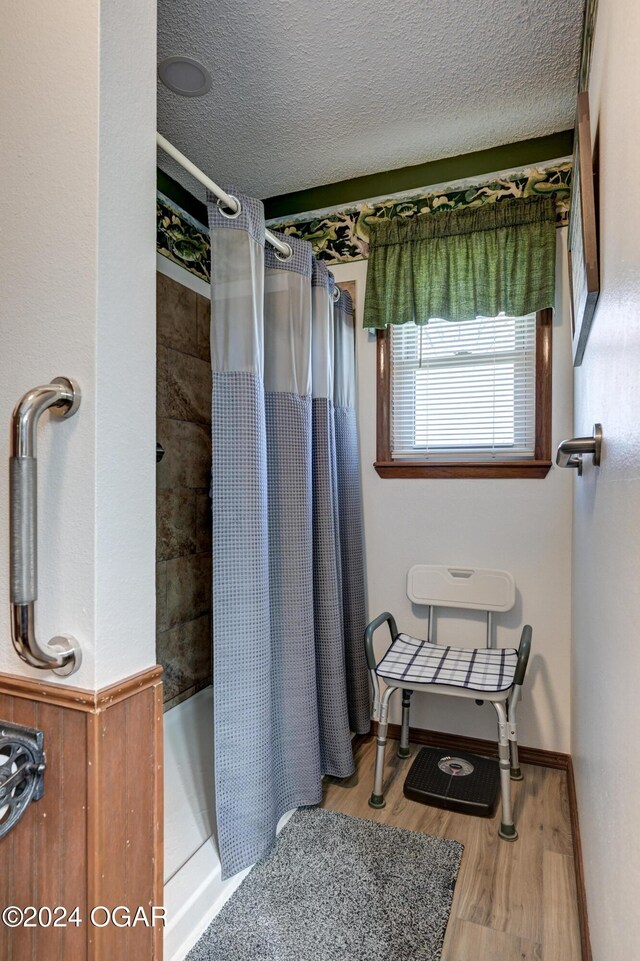 bathroom with wood-type flooring, a textured ceiling, and curtained shower