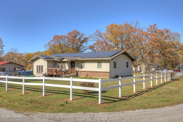 ranch-style house with a front yard and solar panels