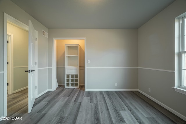 unfurnished bedroom featuring a spacious closet, a closet, and light wood-type flooring