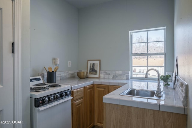 kitchen with sink, electric stove, and tile counters