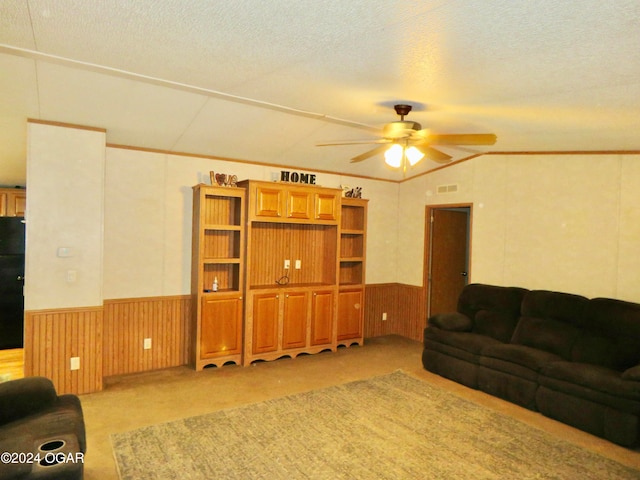 carpeted living room with a textured ceiling, vaulted ceiling, ceiling fan, and wooden walls