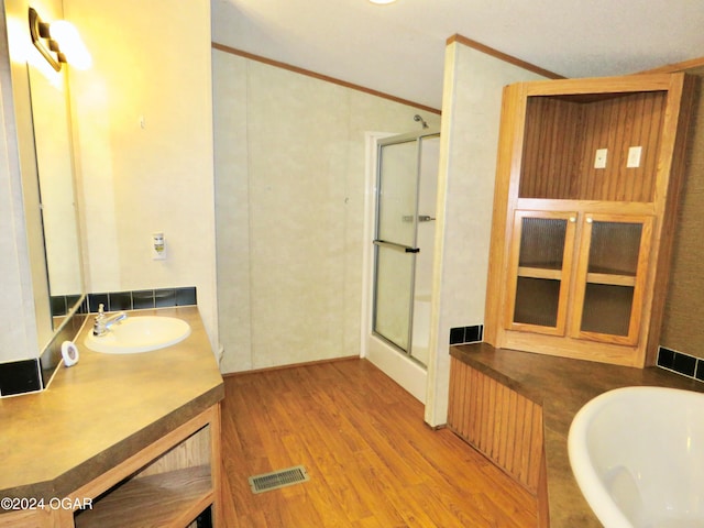 bathroom featuring crown molding, hardwood / wood-style floors, vanity, and walk in shower