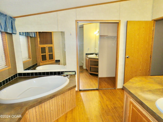 bathroom featuring a washtub, vanity, crown molding, hardwood / wood-style floors, and toilet