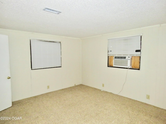 carpeted spare room with cooling unit, ornamental molding, and a textured ceiling