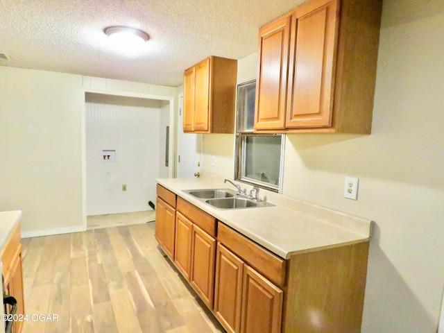 kitchen featuring sink, a textured ceiling, and light wood-type flooring