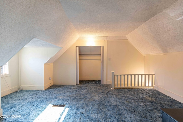 bonus room with a textured ceiling, dark carpet, and lofted ceiling