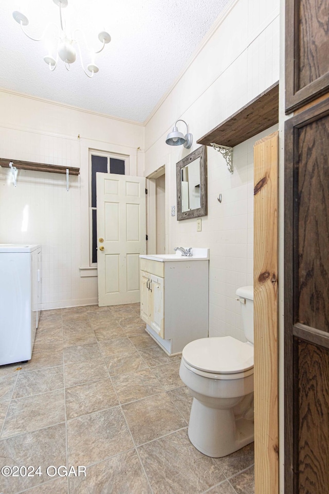 bathroom with vanity, an inviting chandelier, toilet, independent washer and dryer, and a textured ceiling