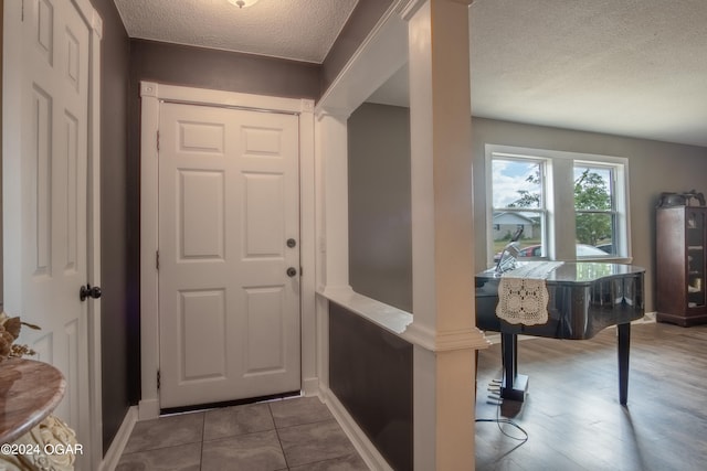 doorway with hardwood / wood-style flooring, a textured ceiling, and decorative columns