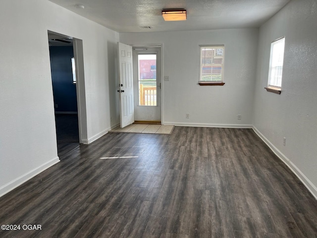 empty room with dark hardwood / wood-style flooring and a textured ceiling