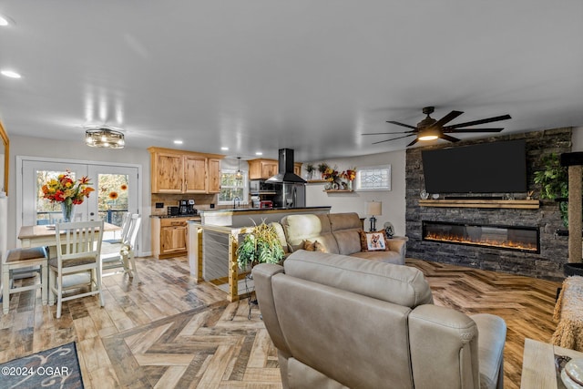 living room with ceiling fan, sink, light parquet floors, and a fireplace