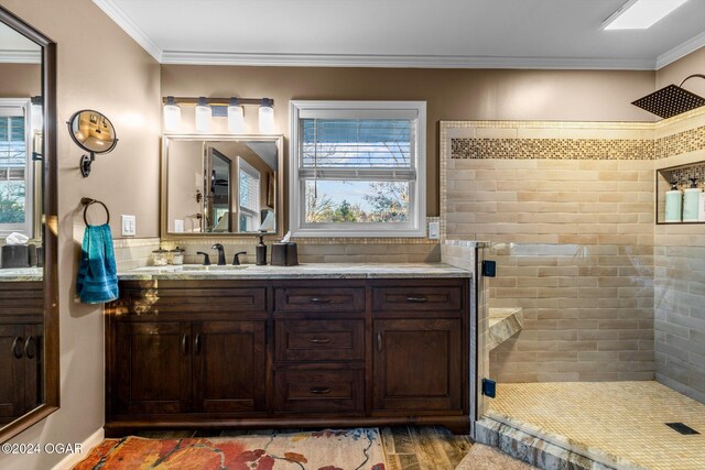 bathroom featuring ornamental molding, a tile shower, and vanity