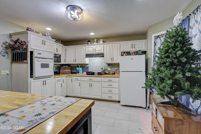 kitchen featuring black appliances, butcher block countertops, white cabinets, and backsplash