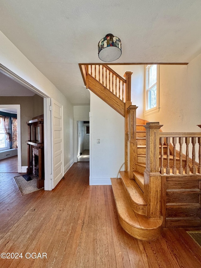 staircase featuring wood-type flooring, a textured ceiling, and a healthy amount of sunlight