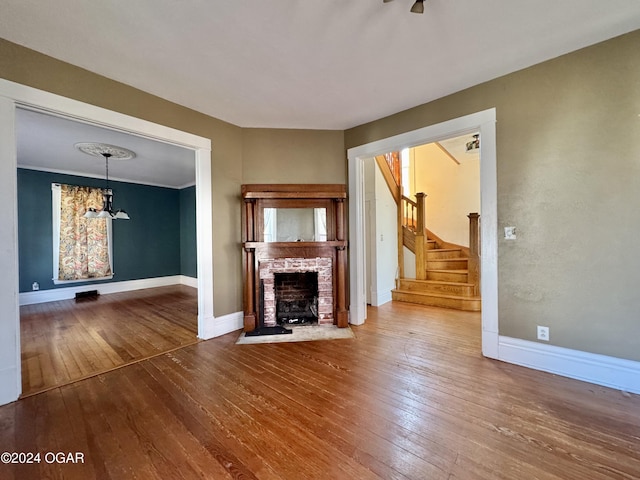 unfurnished living room with wood-type flooring and an inviting chandelier