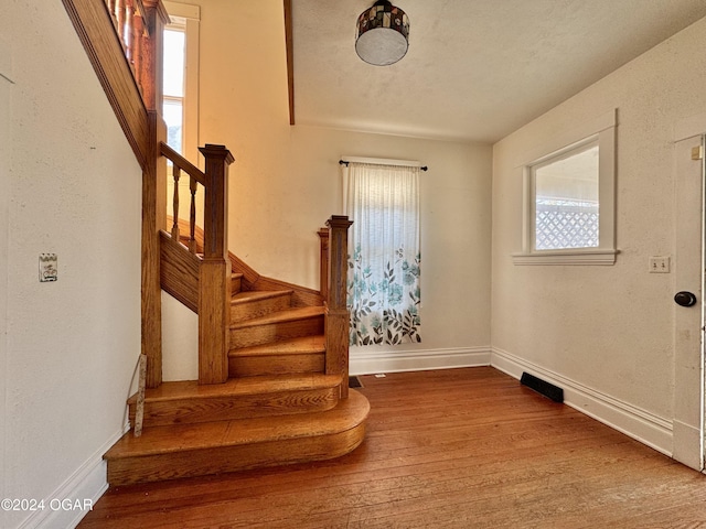 stairway with hardwood / wood-style flooring and a healthy amount of sunlight