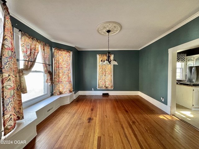 unfurnished dining area with a chandelier, wood-type flooring, and crown molding