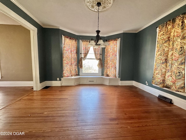 unfurnished dining area with a notable chandelier, wood-type flooring, and ornamental molding