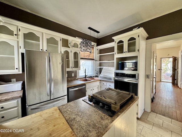 kitchen featuring decorative light fixtures, stainless steel appliances, plenty of natural light, and light hardwood / wood-style floors