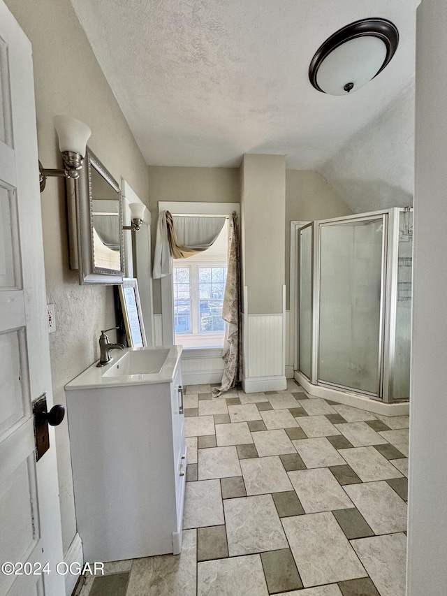 bathroom featuring a textured ceiling, vanity, vaulted ceiling, and a shower with door