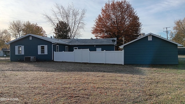 back of property with central AC and a yard