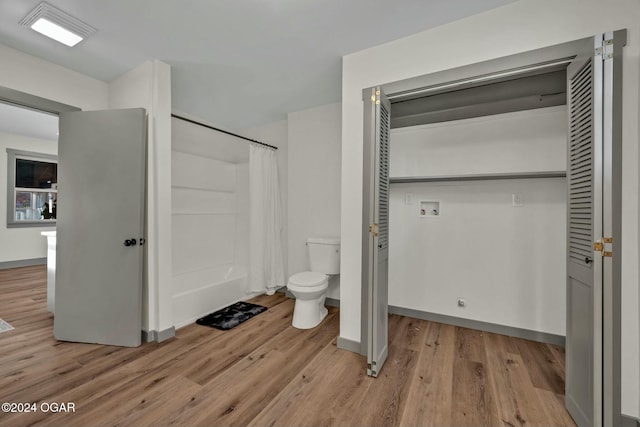 bathroom with hardwood / wood-style floors, a shower with curtain, and toilet