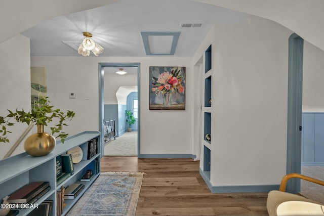 hall with wood-type flooring and vaulted ceiling