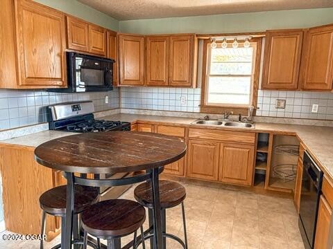 kitchen with black appliances, decorative backsplash, and sink