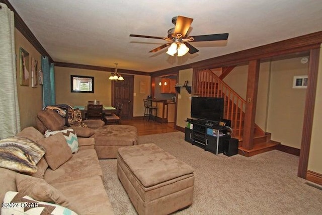 living room with ceiling fan with notable chandelier, carpet floors, and ornamental molding