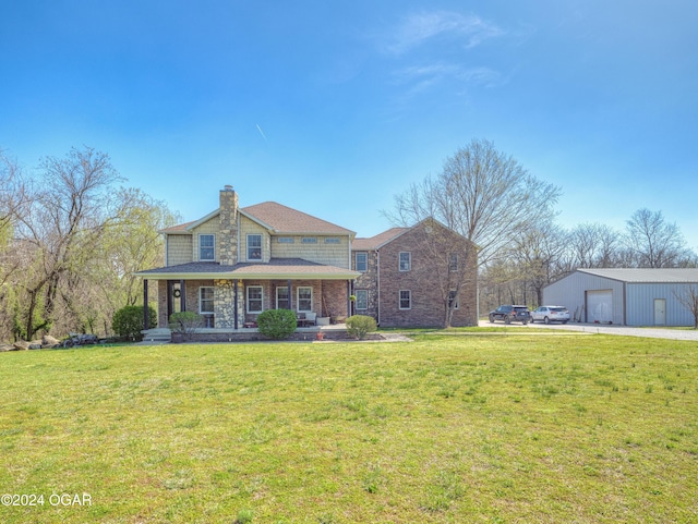 back of property with a lawn, a garage, an outdoor structure, and covered porch