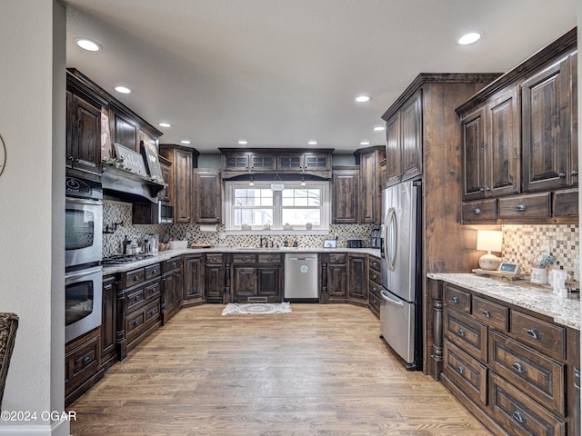 kitchen with dark brown cabinetry, light hardwood / wood-style flooring, and appliances with stainless steel finishes