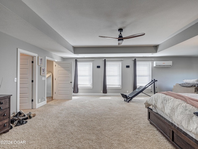 carpeted bedroom featuring an AC wall unit, ceiling fan, a tray ceiling, and a textured ceiling