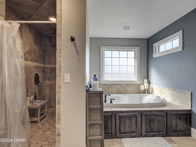 bathroom featuring a textured ceiling and shower with separate bathtub