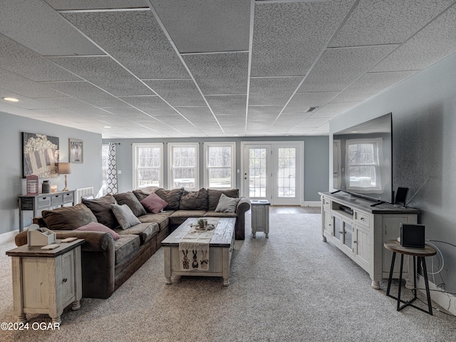 living room featuring light carpet and a paneled ceiling