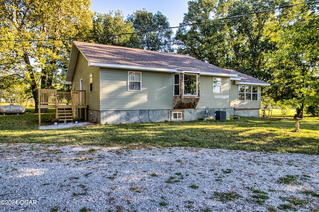 view of front of property with a front yard, a wooden deck, and central AC