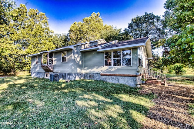 view of front of property featuring cooling unit and a front lawn