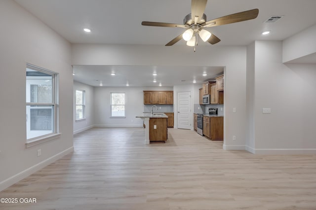 kitchen featuring appliances with stainless steel finishes, light wood-type flooring, sink, an island with sink, and a breakfast bar area