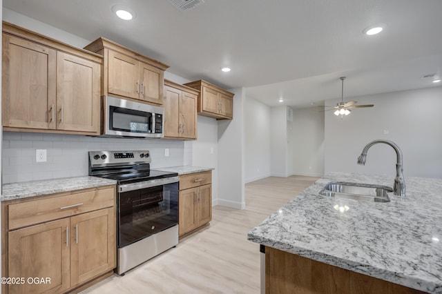 kitchen featuring stainless steel appliances, decorative backsplash, sink, light stone counters, and light hardwood / wood-style flooring