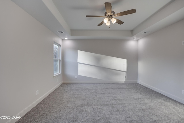 carpeted empty room featuring ceiling fan and a tray ceiling