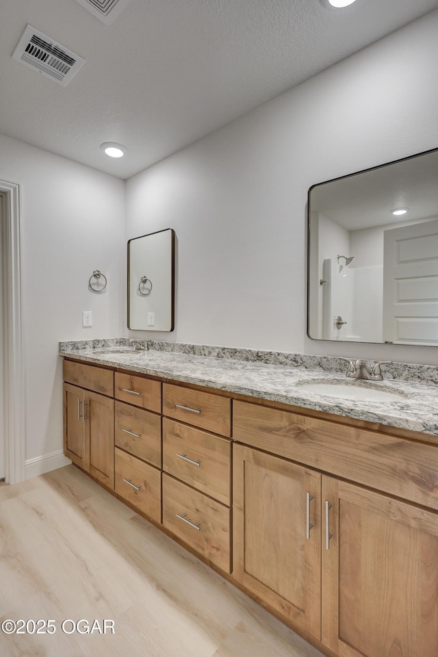 bathroom with hardwood / wood-style flooring, walk in shower, and vanity