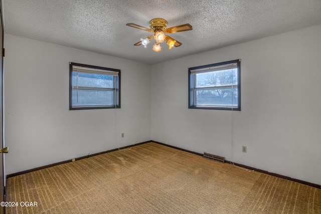 carpeted empty room featuring a textured ceiling, ceiling fan, and a healthy amount of sunlight