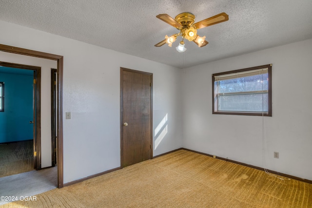 unfurnished bedroom featuring ceiling fan, light colored carpet, and a textured ceiling