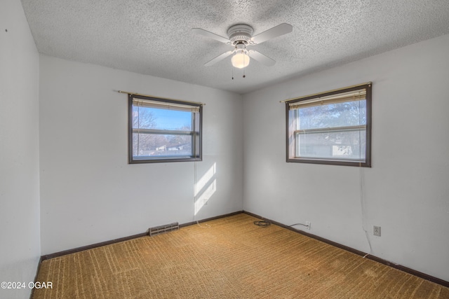 unfurnished room with a textured ceiling, plenty of natural light, and ceiling fan