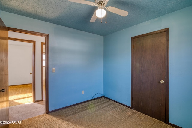 unfurnished bedroom with light carpet, a textured ceiling, a closet, and ceiling fan