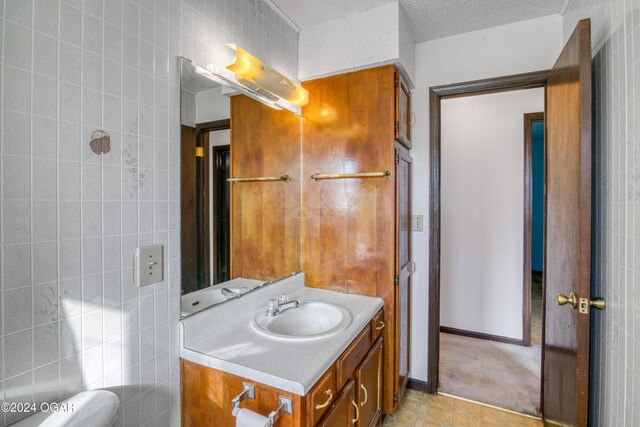 bathroom featuring vanity, a textured ceiling, and tile walls