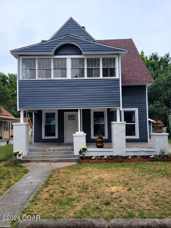 view of front of house with a porch and a front yard