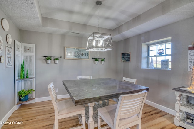 dining area with a textured ceiling and light wood-type flooring