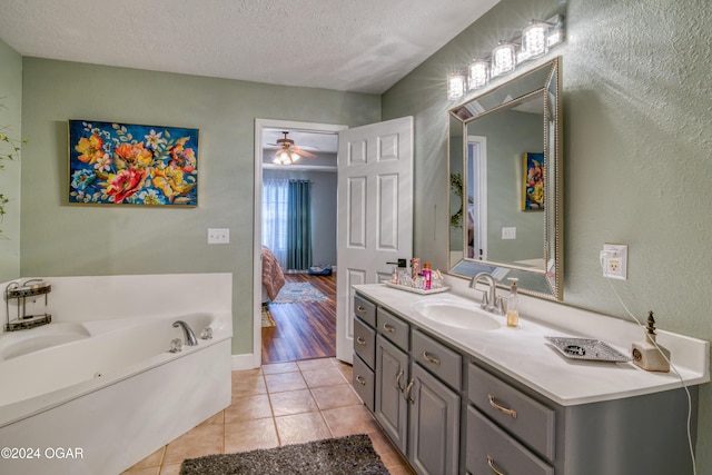 bathroom featuring vanity, a bathing tub, tile patterned flooring, ceiling fan, and a textured ceiling