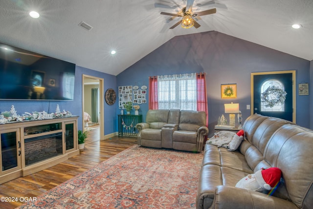 living room with a textured ceiling, ceiling fan, wood-type flooring, and vaulted ceiling