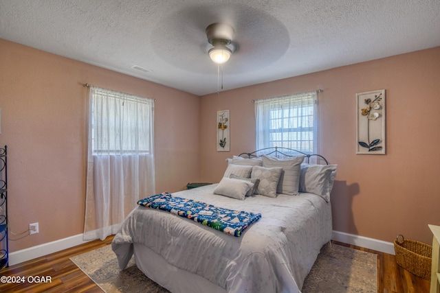 bedroom featuring ceiling fan, dark hardwood / wood-style flooring, and a textured ceiling