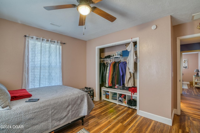 bedroom with a textured ceiling, a closet, ceiling fan, and dark wood-type flooring